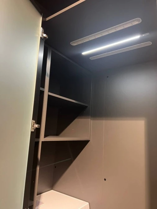 Interno cabina con illuminazione completa di griglia di areazione per utilizzo di lavatrice e asciugatrice.