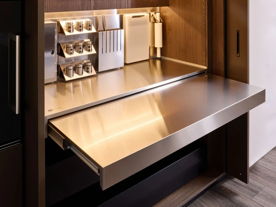 Particolare del piano di lavoro estraibile in acciaio inox con porta spezie, porta rotoli e porta coltelli